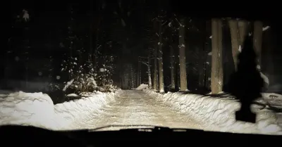 A dark, icy road at night illuminated by the flashing blue lights of an emergency vehicle, illustrating the Thames Valley Police negligence case