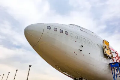 The nose of a Boeing widebody aircraft on the ground against a cloudy sky