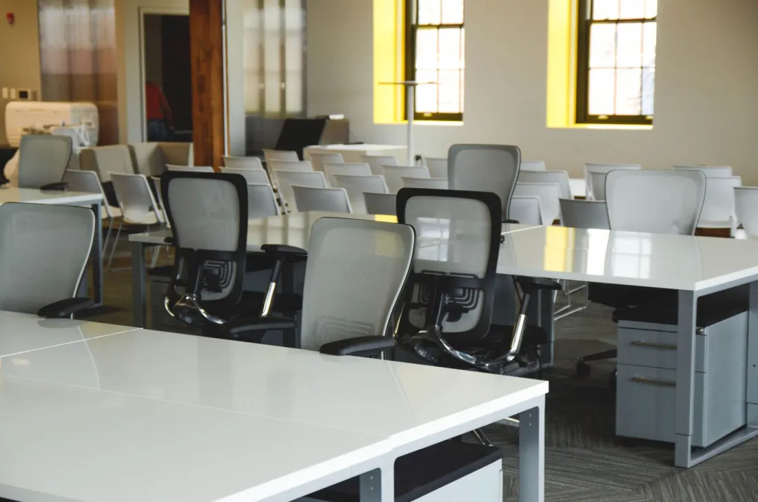 Empty open-plan office with rows of desks and chairs, representing the employers covered by EU pay transparency directive transposition