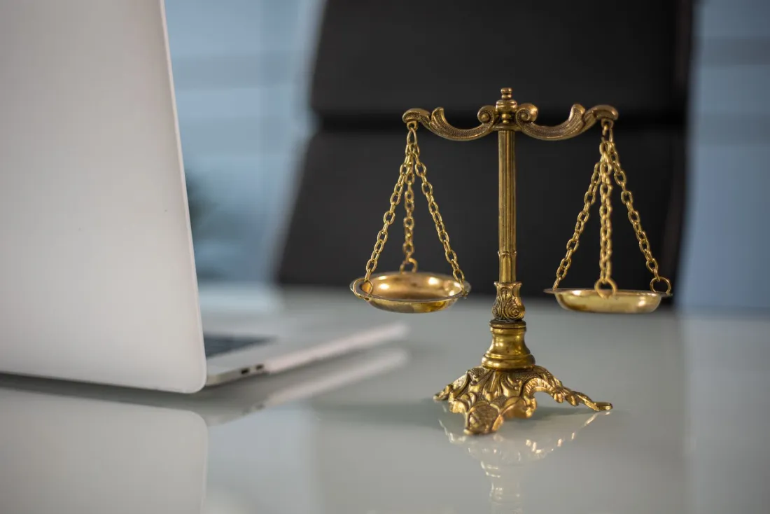 Brass balance scales beside a laptop, symbolising compensation and burden of proof under the EU pay transparency directive
