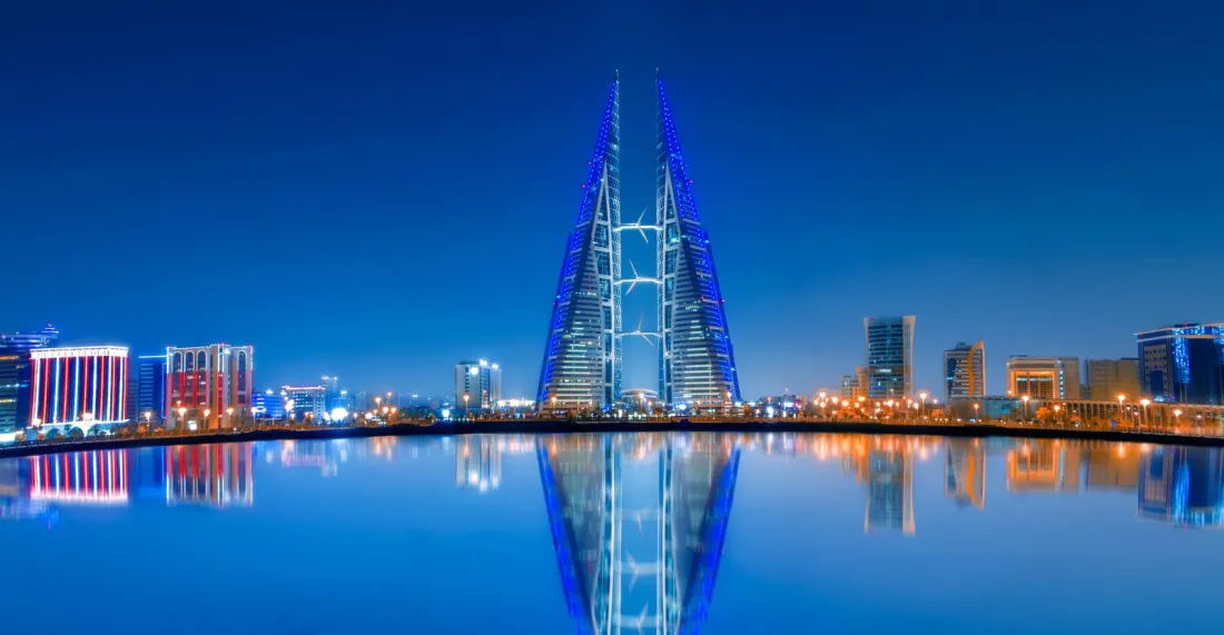 Bahrain World Trade Center reflected in the water at dusk, illustrating the Bahrain DMTT under Decree-Law No. 11 of 2024