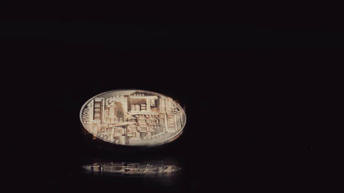 Close-up of a cryptoasset coin on a dark surface, illustrating why overseas crypto firms need FCA authorisation to serve UK consumers