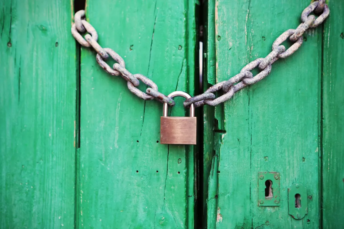 Padlocked chain on a green door, illustrating the blocking clause in China's draft anti-corruption law on foreign investigations