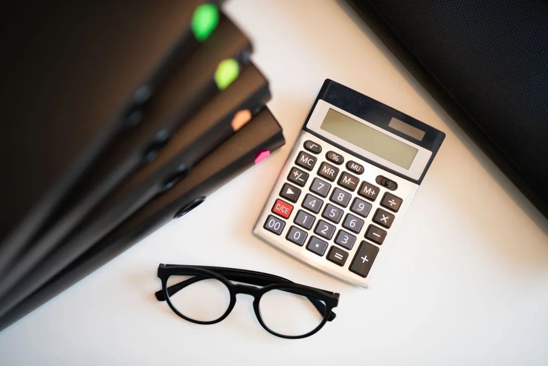 Calculator, glasses and case files on a desk, illustrating how EU cartel fines are calculated under the 2006 Guidelines on fines