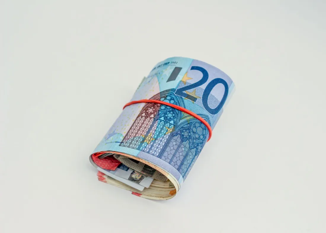 Rolled euro banknotes held by a rubber band, illustrating why EU cartel fines are usually payable while an appeal runs