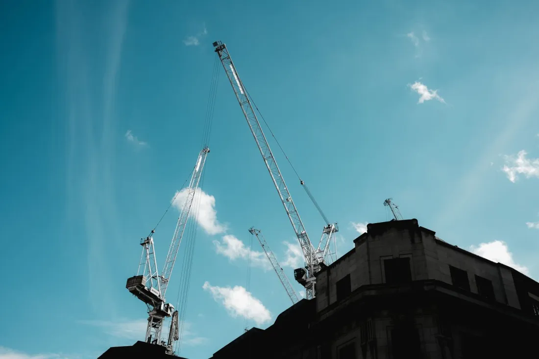 Tower cranes above a city building site, illustrating bid rigging in public procurement and CMA cartel fines