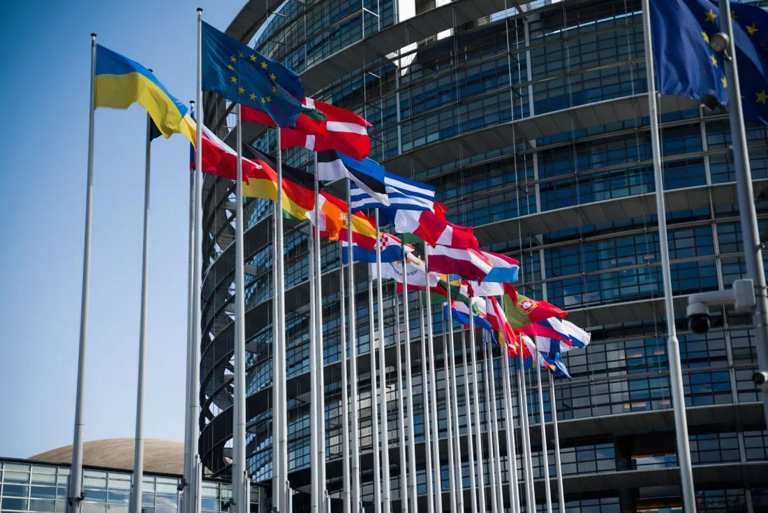Flags of EU member states outside a parliament building, representing the EU Representative Actions Directive and cross-border collective redress