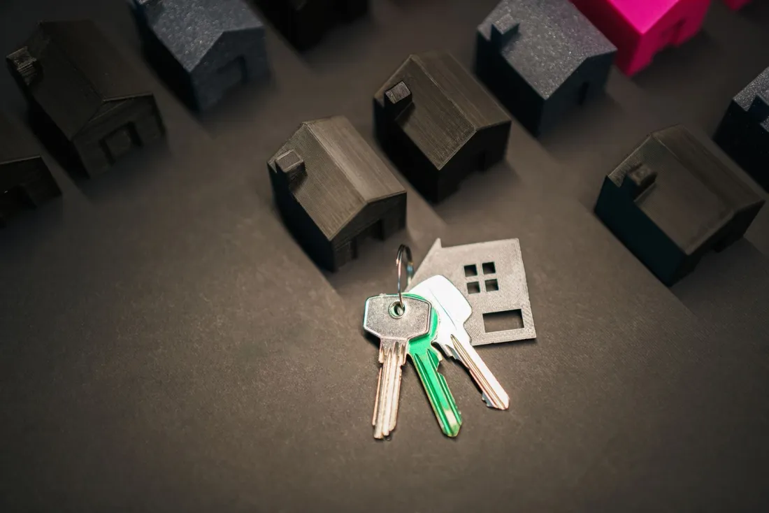 Miniature house models and a set of keys, illustrating the question can I get residency in Latvia if I buy a house