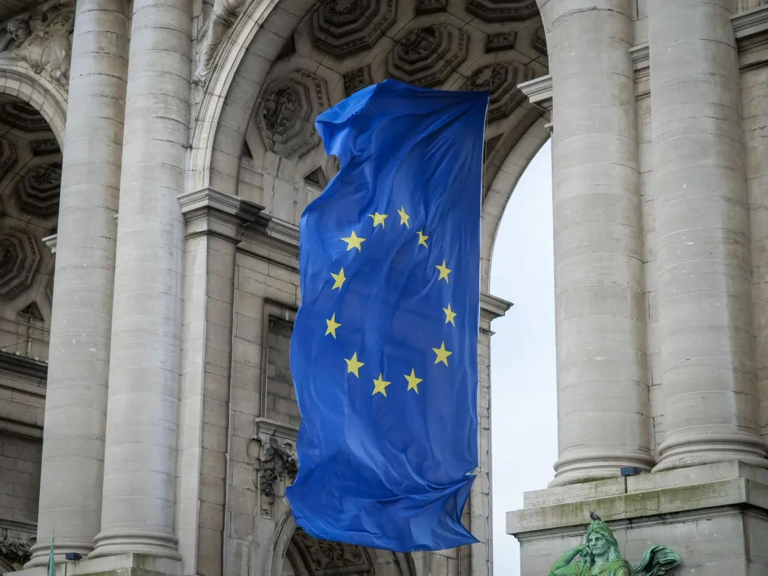 European Union flag hanging beneath the Cinquantenaire arch in Brussels, illustrating the EU AI Act timeline