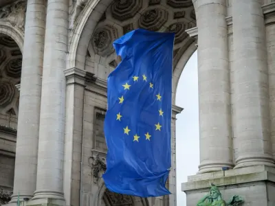 European Union flag hanging beneath the Cinquantenaire arch in Brussels, illustrating the EU AI Act timeline