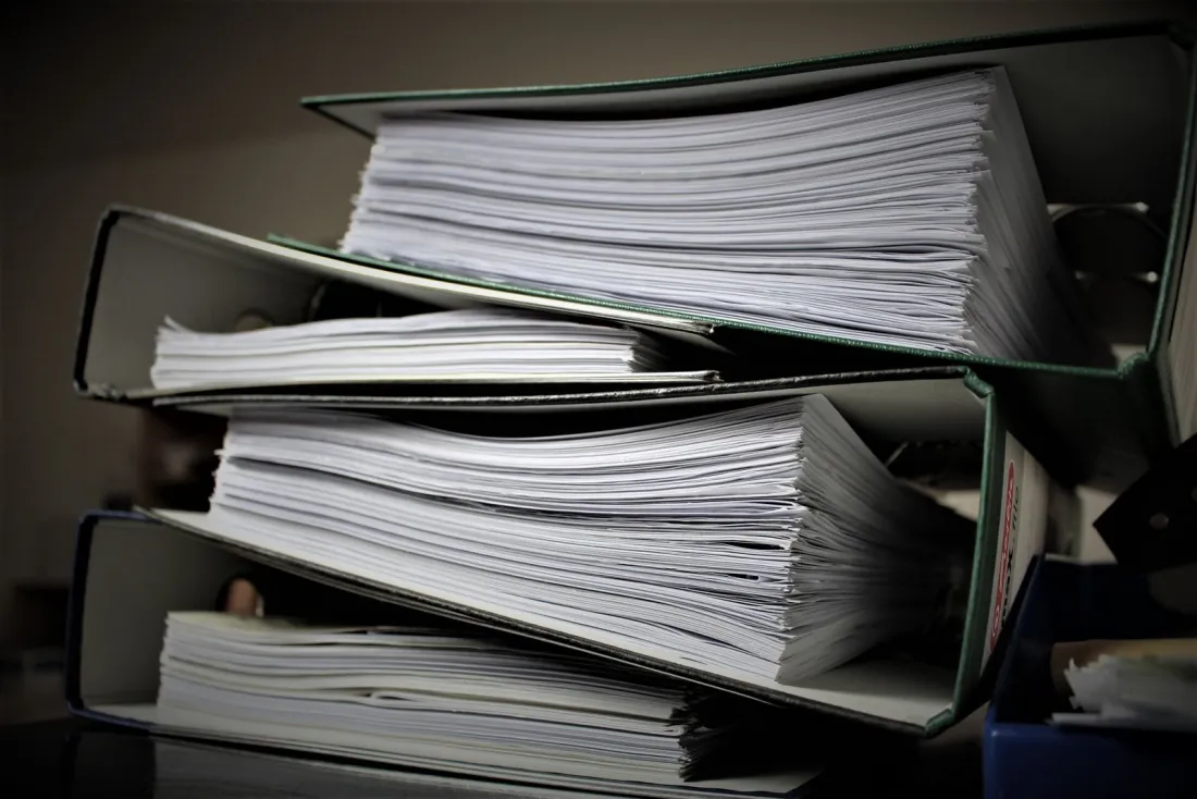 Stacked binders of paper records, illustrating the entry data importers need to file IEEPA tariff refunds through CAPE