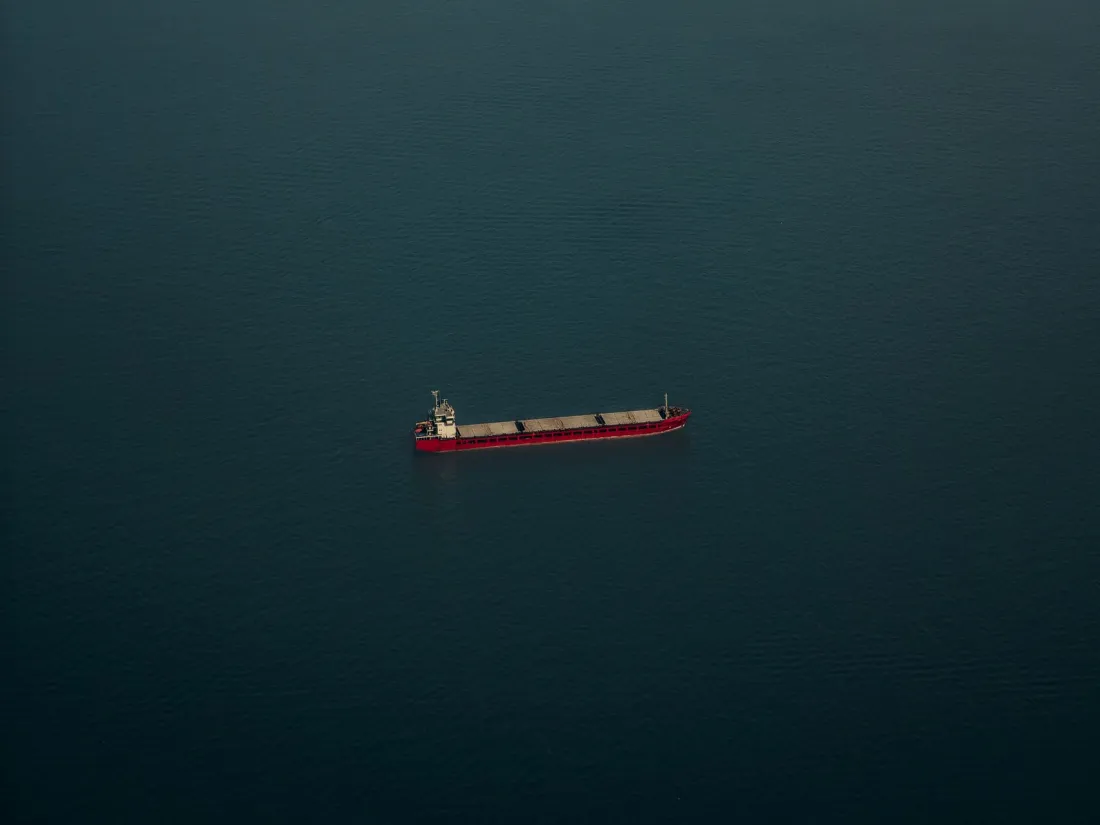 Aerial view of a lone cargo ship on open sea, illustrating what war risk insurance covers