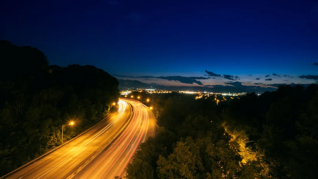 Light trails on a curving highway at dusk, illustrating how modified comparative negligence in New York now bars drivers who are mostly at fault