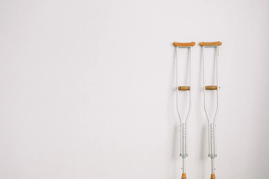 A pair of crutches against a white wall, illustrating the serious injury threshold in New York after the 90/180-day category was deleted