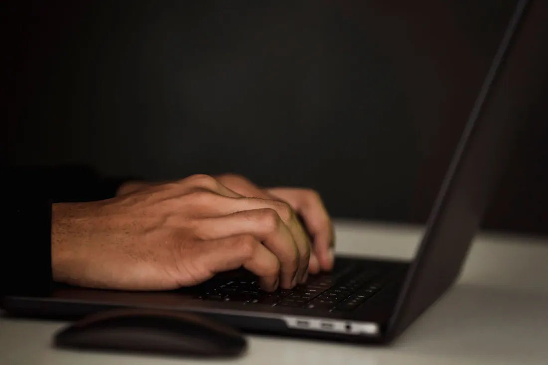 Hands typing on a laptop in a dark room, illustrating the ChatGPT law enforcement referral question at the heart of the OpenAI lawsuit