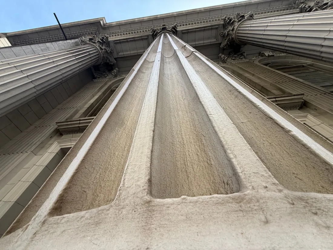 Looking up a fluted stone column of a San Francisco civic building, representing the OpenAI forum non conveniens fight in federal court
