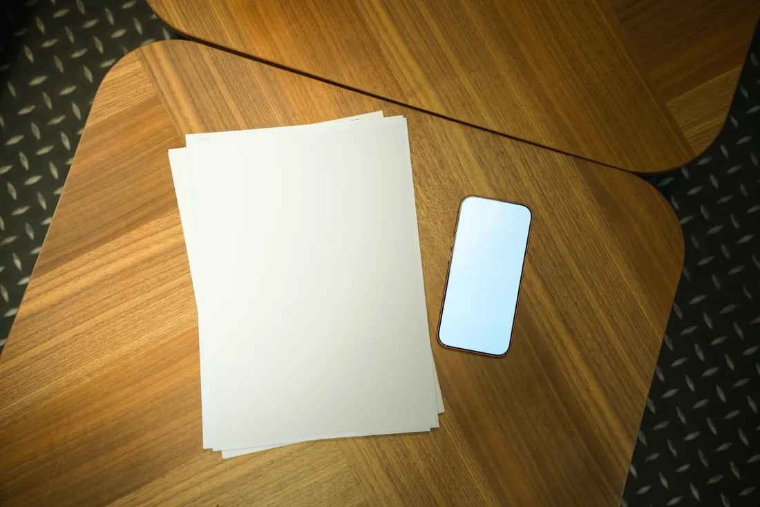 Smartphone with a blank screen beside a stack of papers, illustrating whether a jury verdict can be reversed in Apple's Taptic Engine patent case