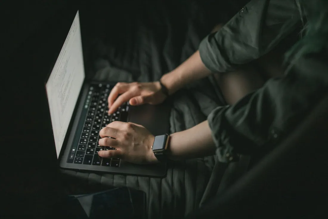 Hands typing a search query on a laptop in a dark room, illustrating whether Google shares your search history with rival search engines