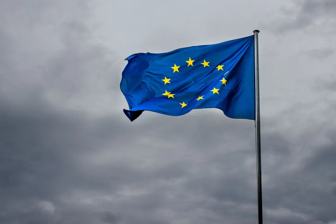 European Union flag flying under storm clouds, representing Google's General Court appeal against the EU search data order