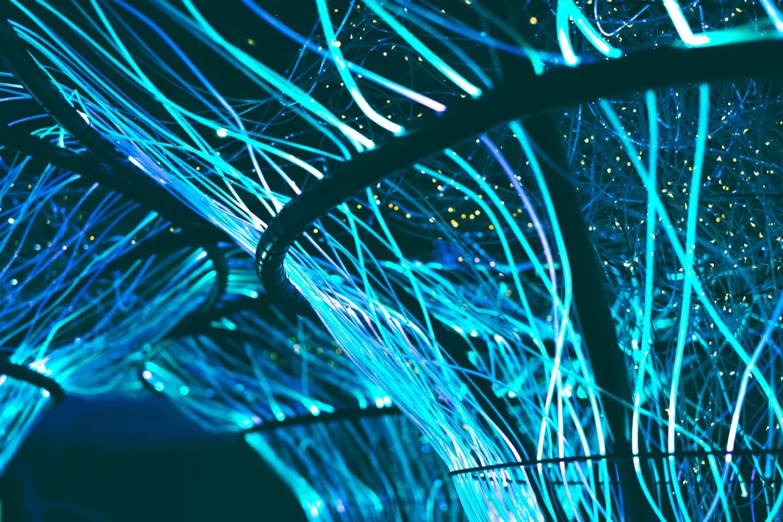 Glowing blue optical fibres in the dark, illustrating generative AI training and how Thomson Reuters v Ross compares with other AI copyright rulings