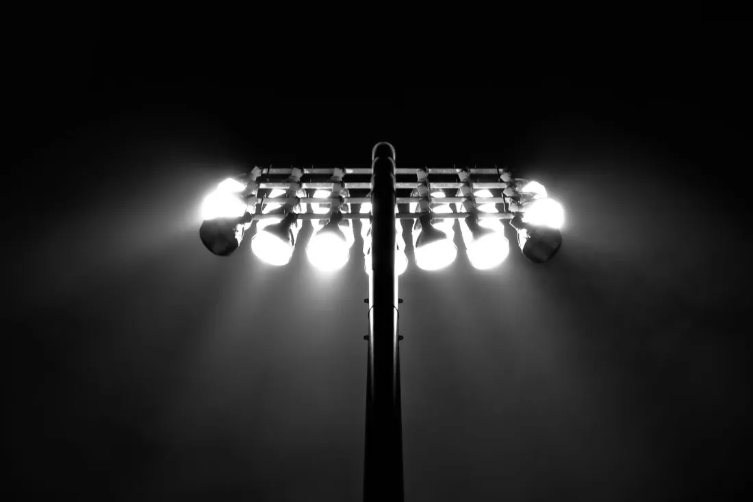 Stadium floodlights glowing against a night sky, illustrating the legal fight over sports event contracts on prediction markets