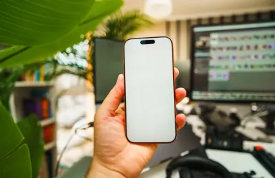 Hand holding a smartphone with a blank screen in an office, illustrating how Ofcom enforces the Online Safety Act against platforms such as Meta