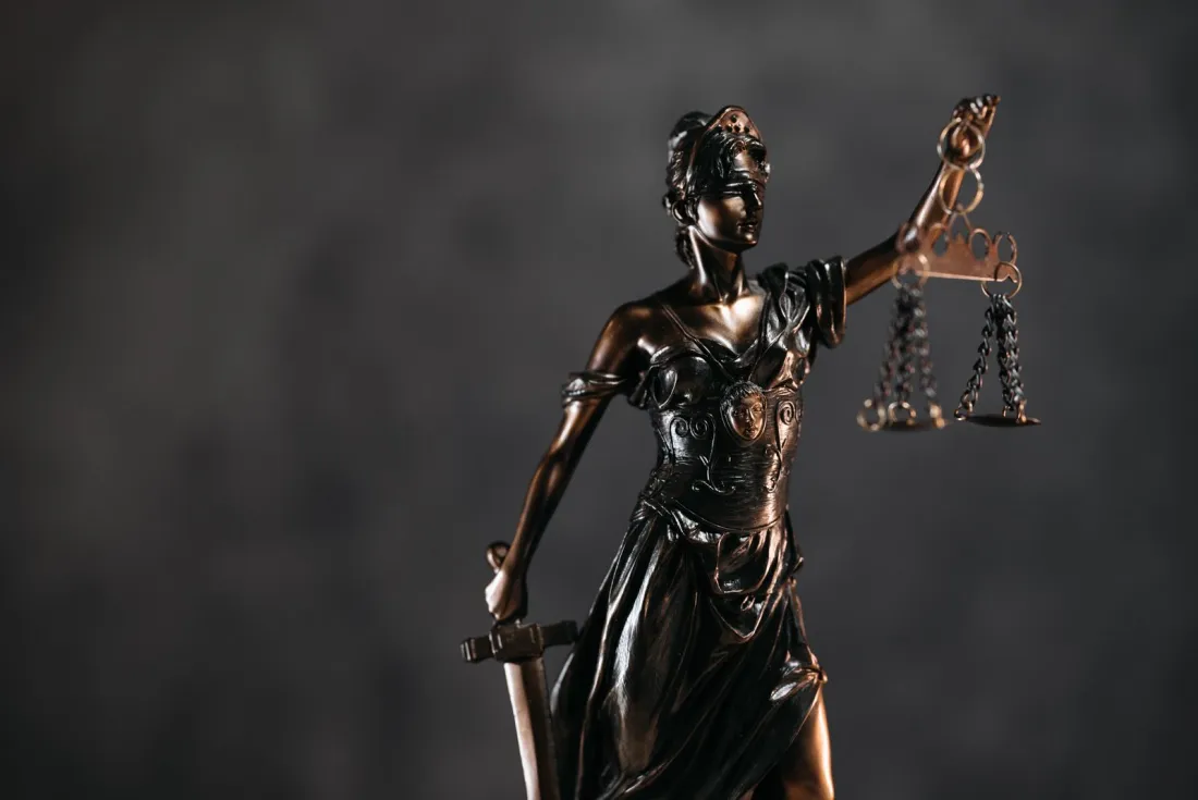 Bronze statue of Lady Justice holding scales, illustrating how Ofcom enforces the Online Safety Act through provisional notices and confirmation decisions