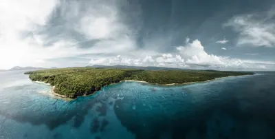 Aerial view of a forested island coastline and reef in Vanuatu, illustrating the Vanuatu citizenship by investment cost and programme