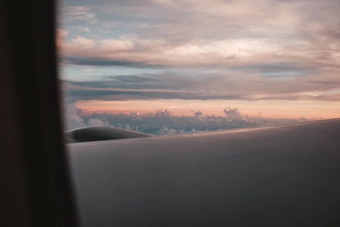 View of an aircraft wing above the clouds at sunset, illustrating Vanuatu passport visa-free travel limits for the EU and UK