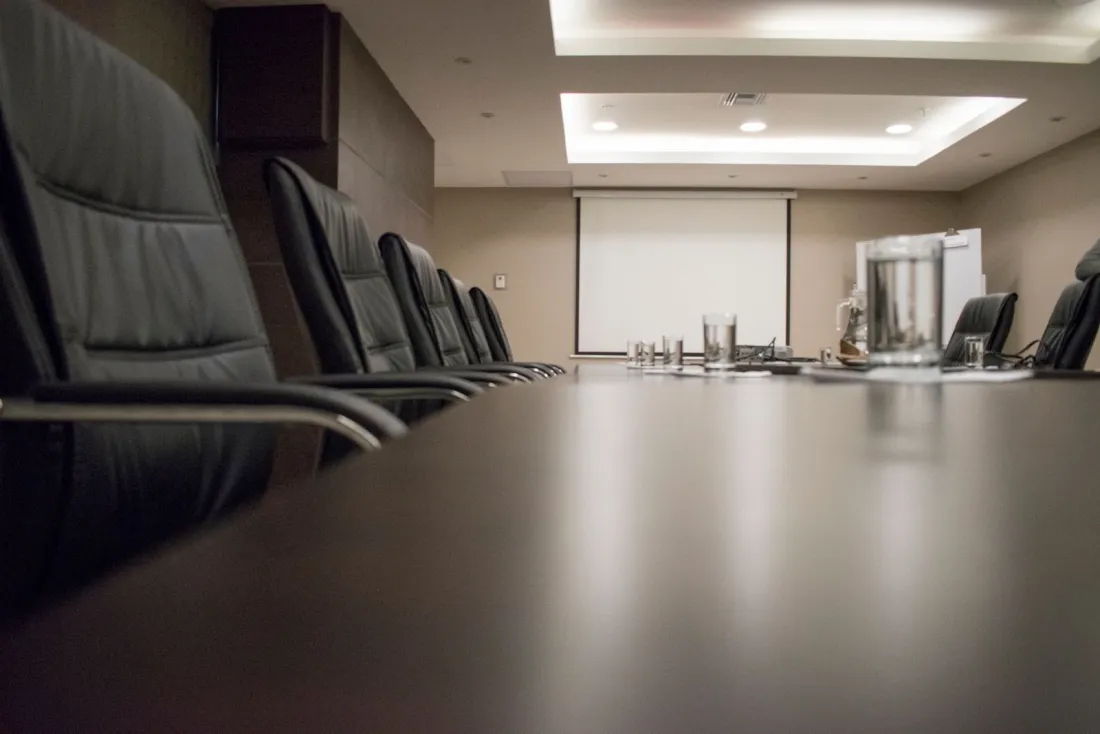 Empty boardroom table with leather chairs, illustrating MiCA licence requirements on governance and EU substance