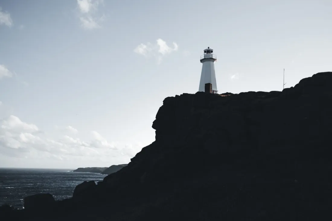 White lighthouse on a dark clifftop above the sea, illustrating a trademark watch service when you register a trademark internationally