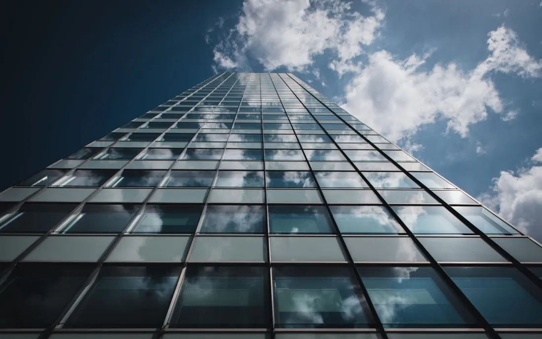 Glass office tower against a blue sky, illustrating limited liability in the branch vs subsidiary choice