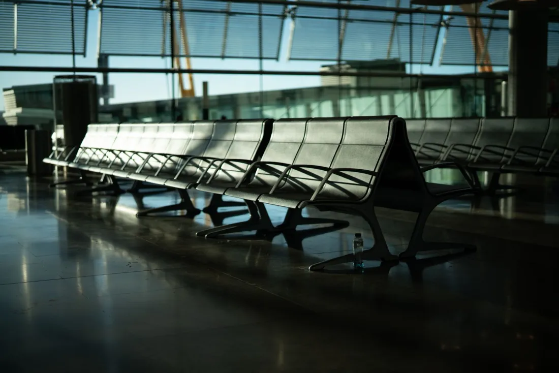 Empty airport departure lounge seating by a glass wall, illustrating how to become non resident for UK tax