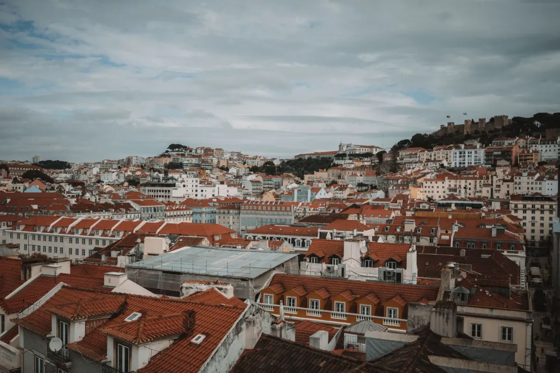 Red-tiled rooftops of Lisbon under a cloudy sky, illustrating Portugal's IFICI regime for people moving abroad from the UK