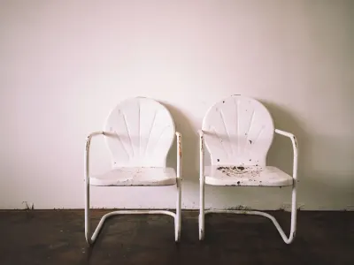 Two empty white chairs side by side against a bare wall, illustrating an international divorce