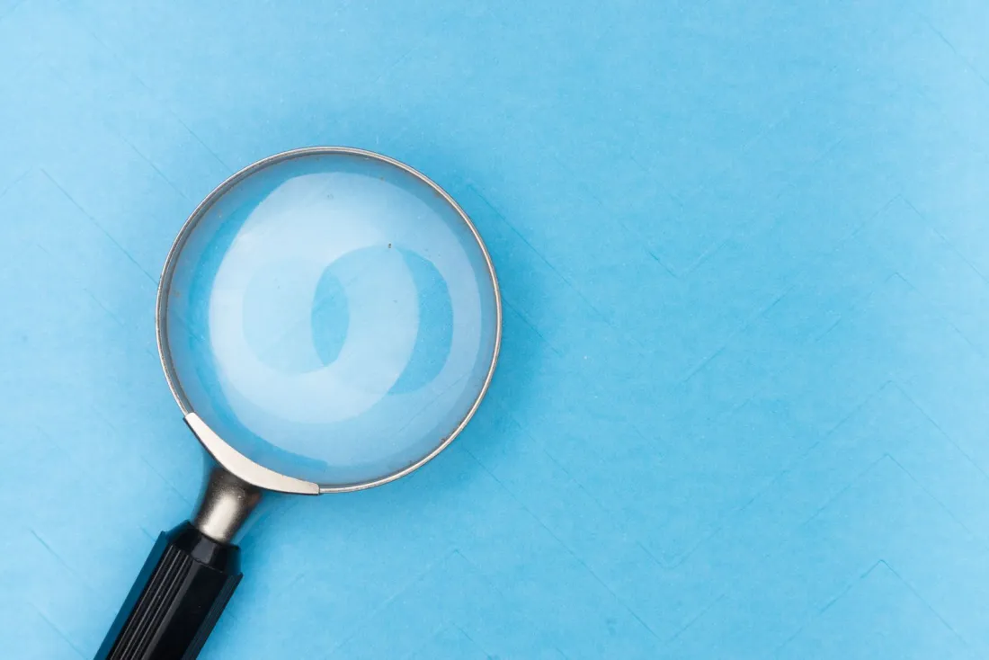 Magnifying glass on a plain blue surface, illustrating due diligence before buying property abroad