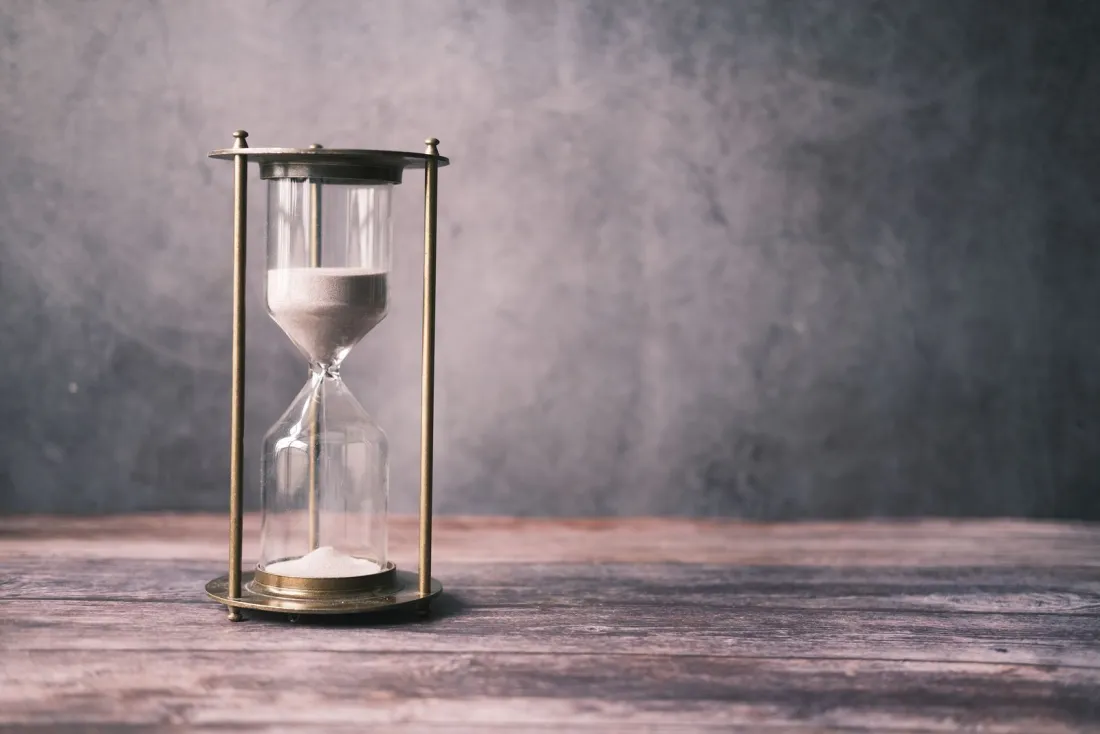 Brass hourglass with sand running out on a wooden table, illustrating the false time-limited offers for which Wayfair was fined by the CMA