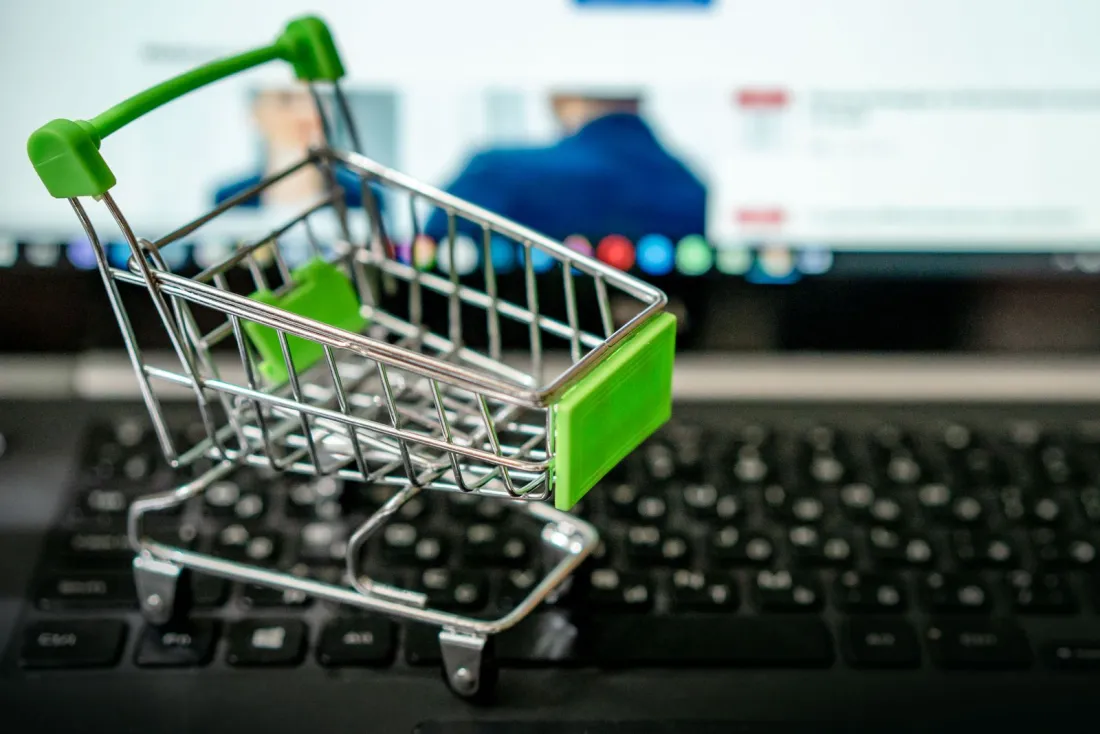 Miniature shopping trolley on a laptop keyboard, representing the online checkout journeys GCs should review after Wayfair was fined