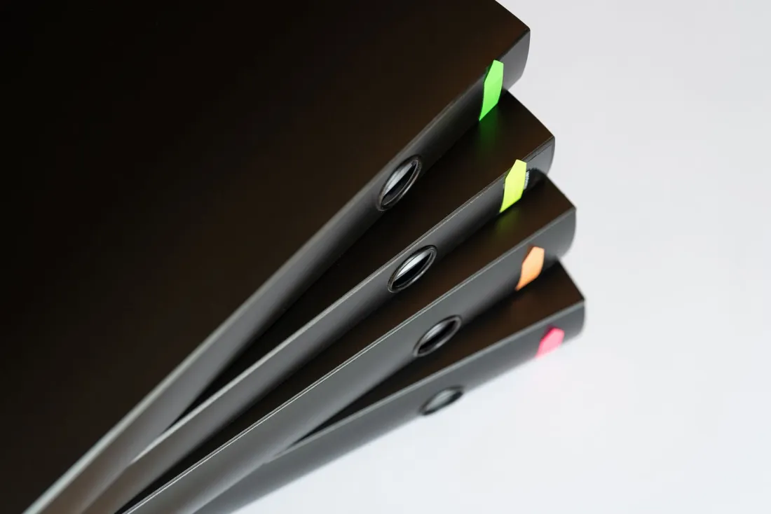 Four black ring binders with coloured tabs stacked at an angle, illustrating the Appendix A documents needed to get a sponsor licence