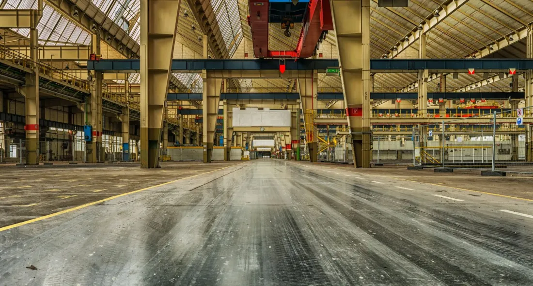 Empty industrial hall with cranes and a bare concrete floor, illustrating what happens to staff when a company goes into administration