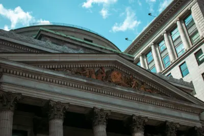Carved neoclassical bank facade with stone columns under a blue sky, illustrating why Bank of America was fined $1.21 billion for AML and sanctions failures