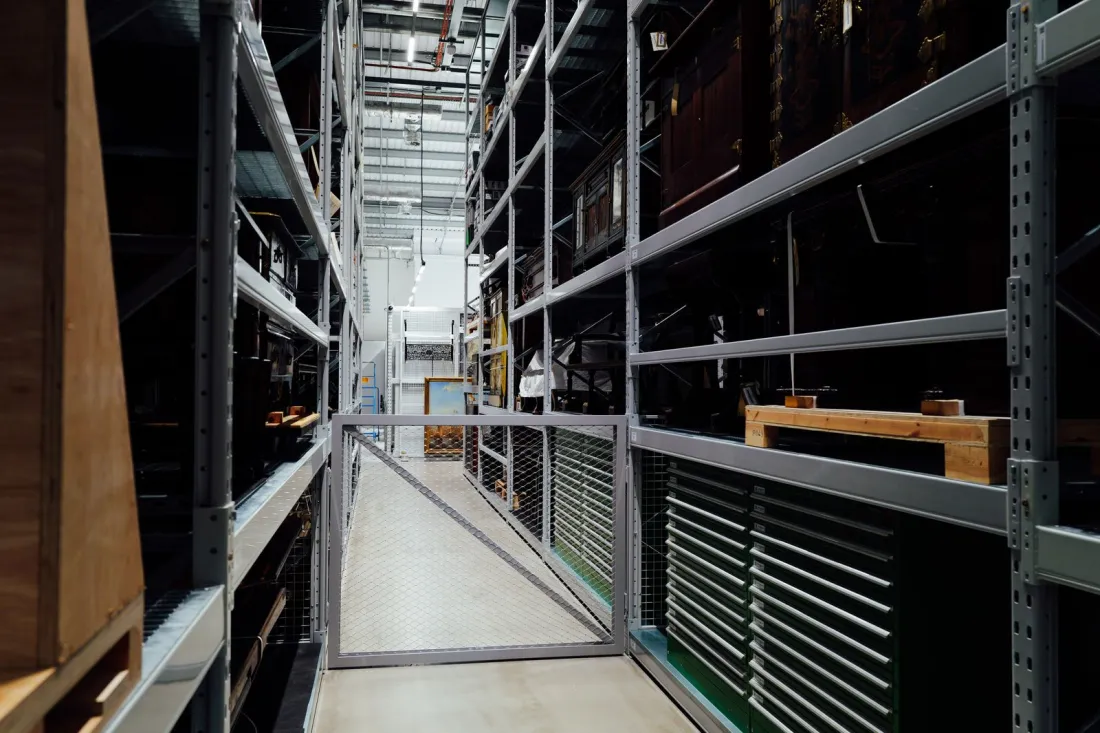 Long aisle between tall metal storage racks in a warehouse, illustrating guaranteed hours and shift rights for zero-hours workers under the Employment Rights Act 2025