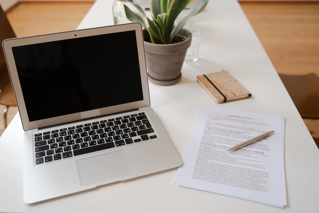 Laptop beside a printed legal document and pen, representing a law firm AI policy and verification of AI legal research