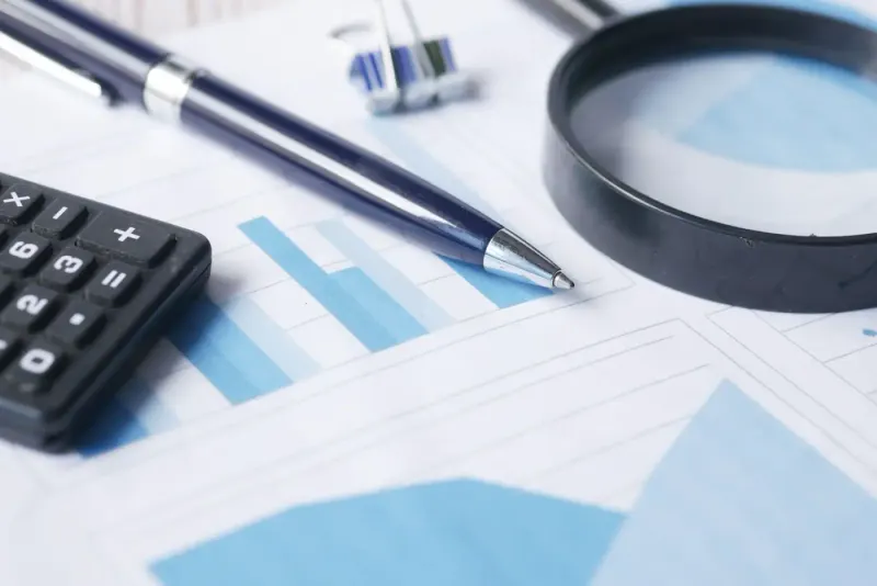 Calculator, pen and magnifying glass on financial charts: advisory & accounting experts and advisers