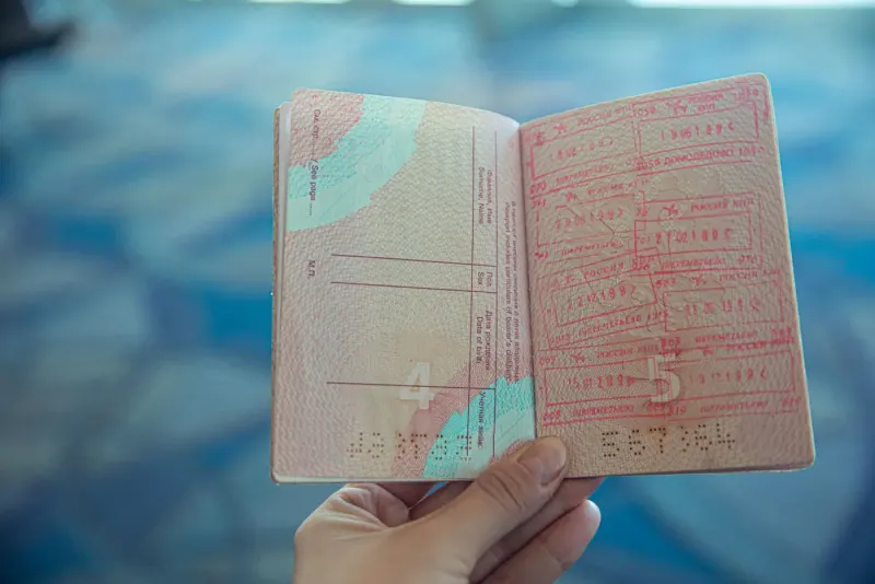 Open passport with travel stamps held in a hand: immigration & citizenship lawyers and advisers