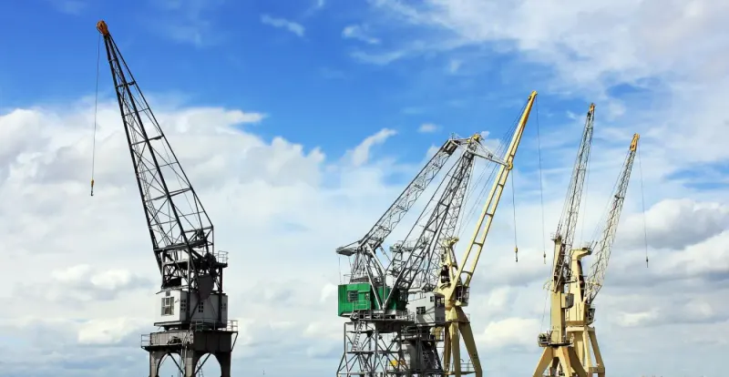 Construction cranes against a blue sky with clouds: construction news and analysis