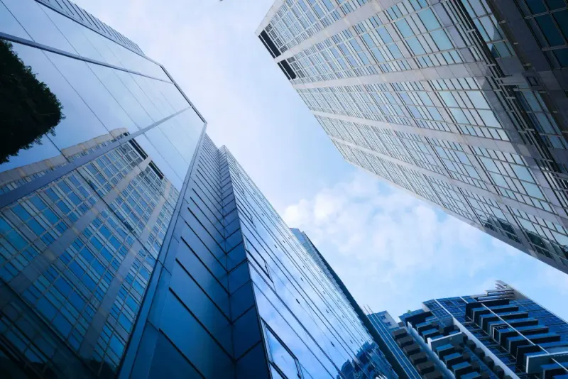 Low-angle view of glass office towers against a blue sky: full lawyers and advisers