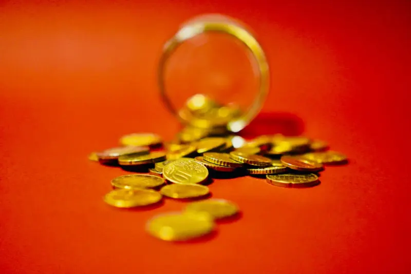 Gold coins spilling from a glass jar on a red background: wealth management news and analysis