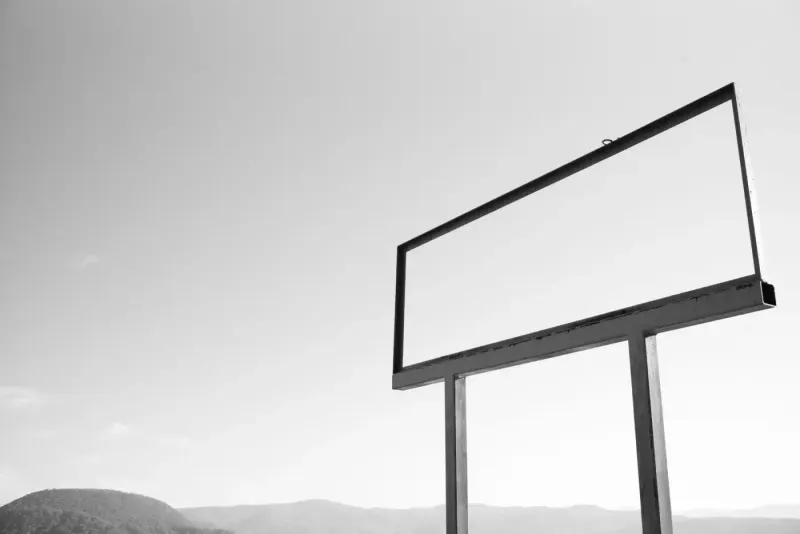 Empty billboard frame in a rural landscape, black and white: advertising experts and advisers