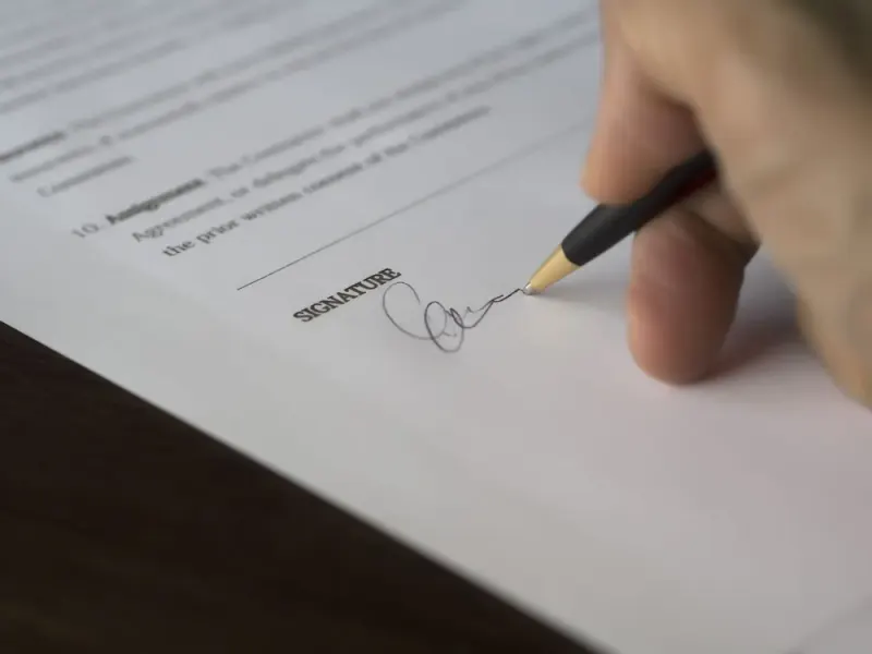 Hand signing a formal contract with a pen: licensing lawyers and advisers